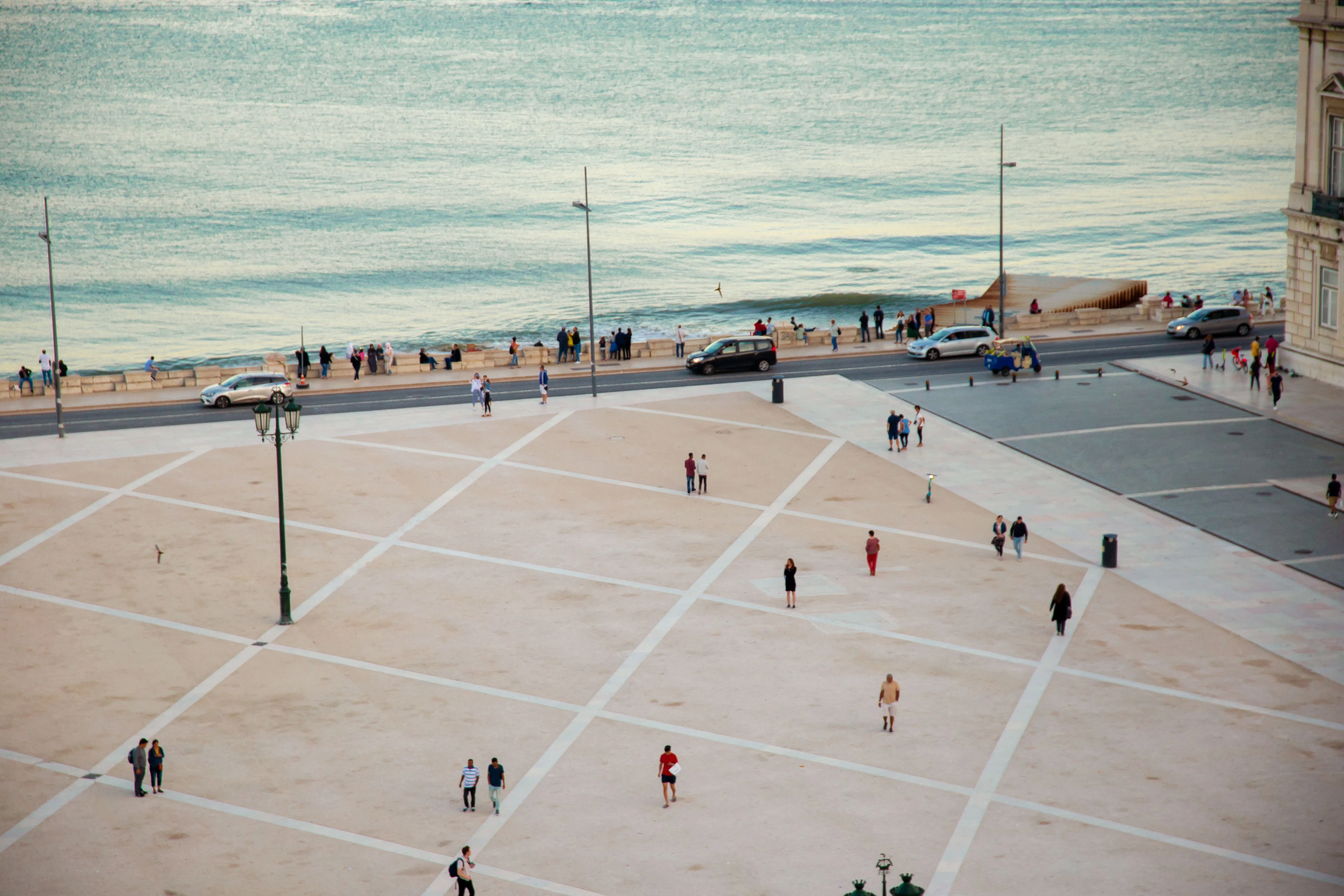 Vista de uma praça ribeirinha em Portugal com pessoas a caminhar